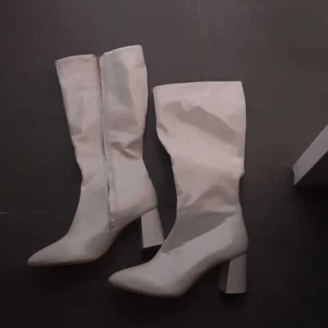 Vita stövlar med klack - Snygga vita stövlar med spetsig tå och klack. De har en dragkedja på sidan för enkel på- och avtagning. Finns slitagemärken