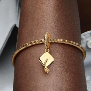 Pandora guldberlock studentmössa - Superfin Pandora berlock i nyskick. Är pläterad med 14 karat guld och formad som en examensmössa. Detaljerad design med texten ”Hard work pays off” på insidan av mössan (se bild 3) och hänget är dekorerat med ett mönster av upphöjda hjärtan. Säljer då jag är en silverperson. Nypris: 899 kr. Pris kan diskuteras.