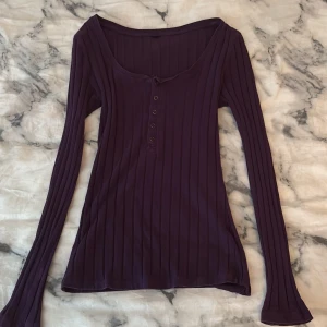 Mörklila ribbad långärmad topp - Säljer en mörklila långärmad topp med ribbad struktur och knappar framtill. Jag kommer inte ihåg vart jag köpt tröjan ifrån eftersom jag har klippt bort prislappen när jag köpte den:)