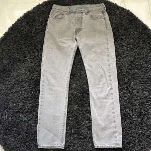 Levi's 501 grå jeans straight fit - Snygga grå Levi's 501 jeans med klassisk rak passform och femficksdesign. Jeansen har en ljusgrå tvätt, knappgylf och ikonisk läderpatch bak i midjan. Tillverkade i robust bomullsdenim som ger en tidlös look. Jag är 181 cm. 