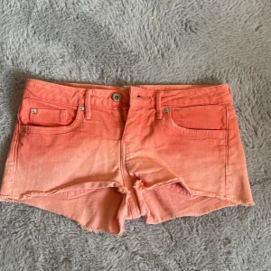Peachfärgade jeansshorts Pepe Jeans - Snygga peachfärgade jeansshorts från Pepe Jeans med råa kanter och klassisk femficksdesign. Shortsen har låg midja, knäppning med knapp och dragkedja samt bälteshällor. Perfekta för varma sommardagar och ger en cool vibe till din outfit.