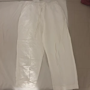 Vita linnebyxor med snörning - Säljer ett par fräscha vita linnebyxor med avslappnad passform och snörning i midjan. Byxorna har raka ben och elastisk midja. För mig sitter de som tre kvarts och är 165 cm lång. 