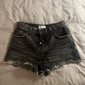 Svarta jeansshorts från Zara - Snygga svarta jeansshorts från Zara med fransiga kanter. Klassisk femficksmodell med bälteshällor och slitna detaljer för en cool vibe. Perfekta till sommaren och lätta att matcha med allt.