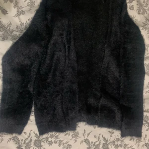 Svart fluffig tröja - Supermjuk och fluffig svart kofta med lång ärm.  Koftan är öppen framtill. 