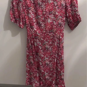 Rosa blommig kortklänning med puffärm - Superfin kortklänning från Gina Tricot i rosa och vitt blommigt mönster. Klänningen har puffiga korta ärmar och en snygg omlott-detalj i midjan. Perfekt för sommarens alla tillfällen!