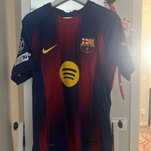 FC Barcelona Cubarsí matchtröja Nike - Säljer en  FC Barcelona matchtröja med Cubarsí och nummer 2 på ryggen. Tröjan är blå och röd med gula detaljer, klubbmärke, Nike-logga och Spotify som sponsor. Kortärmad modell i lätt funktionsmaterial, perfekt för fotboll eller att bära som supporter.player versión ,storlek M