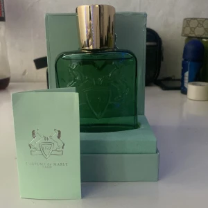 Parfums de Marly Greenley EdP - Greenley från Parfums de Marly är en lyxig parfym i en grön glasflaska med guldfärgad kork. Flaskan har ett elegant reliefmönster med två hästar och en sköld med årtalet 1743. Kommer i original mintgrön box och medföljande booklet.