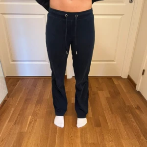 Mörkblå mjukisbyxor från Gina Tricot - Mörkblå mjukisbyxor från Gina Tricot i supermjuk kvalitet. Byxorna har normal passform, raka ben och dragsko i midjan för skön känsla. Perfekta för chill dagar eller när du vill vara bekväm men ändå se snygg ut. Kan vikas ner om man vill ha dom mer långmidjade