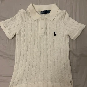 Polo stickad pikétröja  - Vit stickad pikétröja från Polo Ralph Lauren med klassisk krage, korta ärmar och broderad marinblå logga på bröstet. Tröjan är i bomull och har ribbade muddar vid ärmslut och nederkant. Använd 1 gång☺️