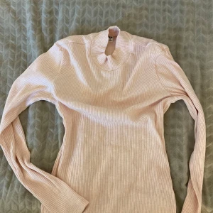Ljusrosa ribbad polotröja Uniqlo XS - Supersöt ljusrosa ribbad polotröja från Uniqlo i storlek XS. Tröjan har lång ärm och en hög krage som ger en clean och stilren vibe. Perfekt att styla med jeans eller kjol för en chill look.