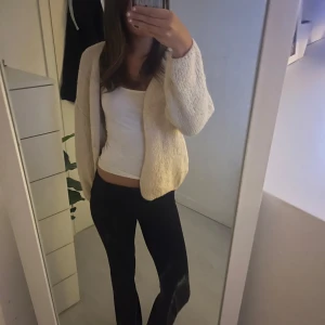 Beige stickad cardigan kofta - Mysig och enkel beige stickad cardigan kofta med avslappnad passform. Koftan är öppen framtill utan knappar eller dragkedja och har långa ärmar. Perfekt att slänga på sig över en topp för en chill och stilren look. Den är i storlek xs/s