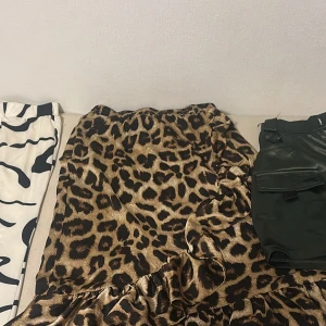 1 för 30 alla för 70 stl M på alla - Snygg långkjol med leopardmönster i bruna och svarta toner. Kjolen har volangdetalj nertill och resår i midjan för en bekväm passform. Materialet är glansigt och ger kjolen en cool look, perfekt för dig som vill sticka ut.