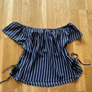 Randig offshoulder topp  - Superfin marinblå och vit randig offshoulder topp från H&M. Toppen har korta ärmar, resår vid axlarna och knytband i sidorna som en extra detalj. Hör av dig om du har några frågor! 😊