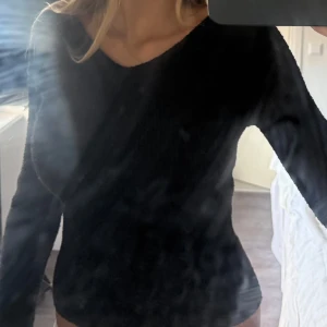 Svart stickad v-ringad tröja - En svart stickad tröja med v-ringning och lång ärm. Tröjan har en enkel och clean look, sitter figurnära och är perfekt för lager-på-lager. Mjuk och skön känsla, passar till allt och är lätt att styla.