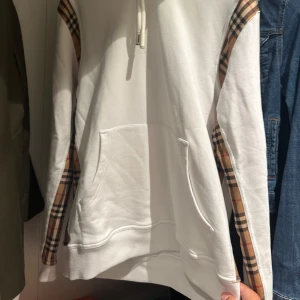 Vit Burberry hoodie  - Säljer en clean vit hoodie från Burberry. Tröjan är suverän. Den är bra i passformen och har inga fläckar eller skador. Den är i mycket bra skick.