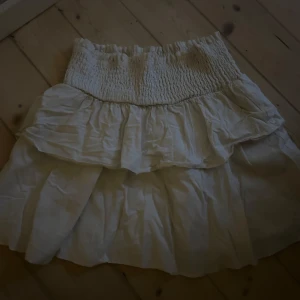 Vit volangkjol från SHEIN - Supersöt vit kortkjol från SHEIN i storlek XS. Kjolen har bred smock i midjan och dubbla volanger som ger en flowy och luftig känsla. Perfekt för dig som gillar en feminin och trendig stil.