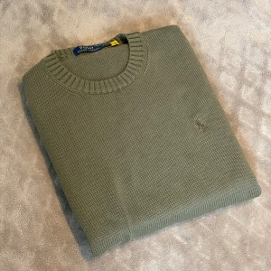 Ralph lauren sweater - 𝗥𝗮𝗹𝗽𝗵 𝗟𝗮𝘂𝗿𝗲𝗻 𝘀𝘄𝗲𝗮𝘁𝗲𝗿 – 𝗼𝗹𝗶𝘃𝗴𝗿ö𝗻, 𝘀𝘁𝗿𝗹 𝗠.               Snygg och tidlös Ralph Lauren-tröja i olivgrön, sitter som en vanlig M. Stickad i mjuk bomullsblandning som gör den både bekväm och hållbar. Mycket fint skick utan fläckar eller hål. Perfekt för kyliga sommarkvällar eller under vårjackan. Passar både till vardags och lite mer uppklätt.  Mått: Axelbredd 43cm och krage till nedre kant 69cm. Skickas mot frakt eller hämtas i Göteborg. Hör gärna av dig vid frågor eller om du vill ha fler bilder!
