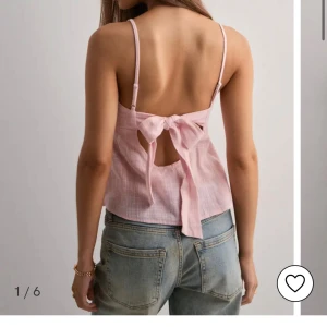 Ljusrosa linnetopp med rosett - Supersöt ljusrosa linnetopp med tunna axelband och en rosett i ryggen. Toppen är ärmlös, har en flowy passform och är gjord i ett lätt, luftigt material som passar perfekt till varma dagar. Snygg att styla med jeans eller kjol.