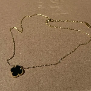 Svart Fyrklöver Guld Halsband - Elegant halsband med en vacker svart fyrklöver som symboliserar lycka och framgång. Halsbandet har en justerbar längd på 40 cm + 5 cm.