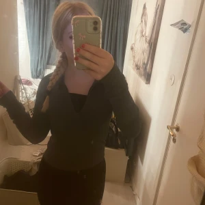 Mörkgrön ribbad träningströja  - Säljer en mörkgrön ribbad overshirt med hel dragkedja framtill och hög krage. Jackan har lång ärm och är i ett stretchigt, mjukt material som sitter snyggt på kroppen. Perfekt att slänga på över en topp för en clean look. Kan också användas till tillexempel träning, säljer för att den kommer inte till använding 💕og pris: 400