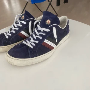 Blå sneakers från Moncler i mocka - Säljer mina Moncler skor pga vill köpa ett par andra skor. Väldigt sköna och snygga Moncler skor i marinblå. Helt autentiska, kartong kommer ej med. Säljer billigt på grund av en skada på ovansidan men den är lagad och syns knappt, nypris ca 2500–3000 kr.
