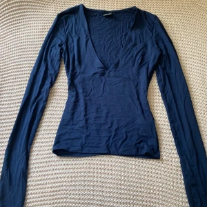 Mörkblå långärmad topp Gina Tricot - Säljer en mörkblå långärmad topp från Gina Tricot i storlek XS. Toppen har djup v-ringning och är figurnära med stretchigt material i bomullsmix. Perfekt till jeans eller kjol för en enkel men snygg look, aldrig använd💞