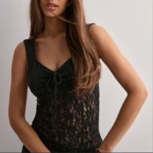 Svart spetsig linnetopp med knyt - Supersnygg svart linnetopp med spetsdetaljer och v-ringning. Toppen är ärmlös och har en söt knytning framtill. Perfekt för dig som vill ha en feminin och trendig look med lite genomskinligt material. Har aldrig använt den och den är helt ny då den är lite för liten för mig! 