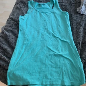 Turkos ärmlös klänning Lindex Kids - Enkel och snygg turkos ärmlös klänning från Lindex Kids i mjuk bomull. Modellen är rak och kort, perfekt för varma dagar. Passar dig som gillar en basic och bekväm stil.