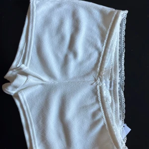 Vita spetskantade shorts Gilly Hicks - Supermjuka vita shorts från Hollister (”Gilly Hicks”) med söt spetskant och liten rosett framtill. De har stretch och är tänkta att vara för pyjamas. Shortsen är HELT nya och har aldrig varit använt, dvs är de helt utan defekter. 