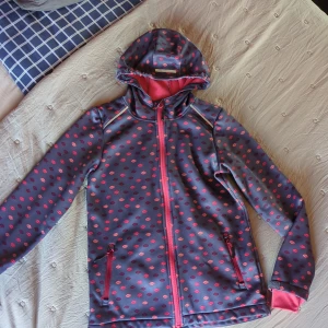 Blå och rosa vindjacka med lövmönster - Snygg vindjacka. Insidan är fodrad med mjuk fleece och ärmarna har rosa muddar sydda på insidan.