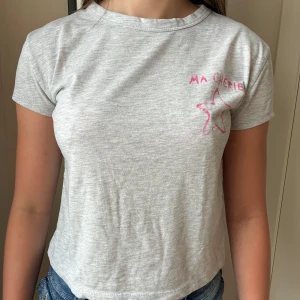 Grå t-shirt  - Grå supersöt t-shirt från Gina Tricot med korta ärmar och rosa tryck med texten 'Ma Chérie' och en stjärna både fram och bak. Säljer pga att den inte passar mig. Tröjan har aldrig används. Pris kan diskuteras!!💕💕