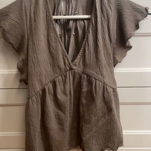 Brun omlottopp med volangärm - Supersöt brun omlottopp med djup v-ringning och knyt i ryggen. Toppen har korta, volangiga ärmar. Skriv för bilder på ❤️