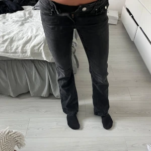 Svarta lågmidjade bootcut jeans - Säljer ett par svarta Levis jeans med bootcut passform. Jeansen har klassisk femficksdesign, silverfärgade knappar och dragkedja. Snygg tvättad svart färg och raka ben som blir lite vidare nertill. Perfekta till sneakers eller boots.