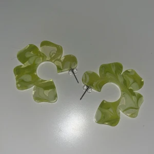 Örhängen  - Snygga örhängen i form av stora blommor med swirlmönster i olika gröna nyanser. Tillverkade i akrylplast och har metallstift. Endast använda 1 gång