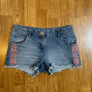 Lowwaist jeansshorts - Lågmidjade blå jeansshorts med broderi på sidorna från pepperts i storlek 152 men skulle säga att de sitter som en xs ungefär, då de är lite för små för mig som annars har s