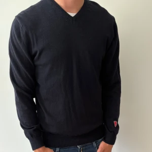 Marinblå v-ringad tröja från Ivanhoe - 100% Merinoull  - Säljer nu en snygg klassisk mörkblåa v-ringad tröja från Ivanhoe med lång ärm och diskret logga på ärmen. Tröjan är i 100% merinoull och passar perfekt till S/M storlekar