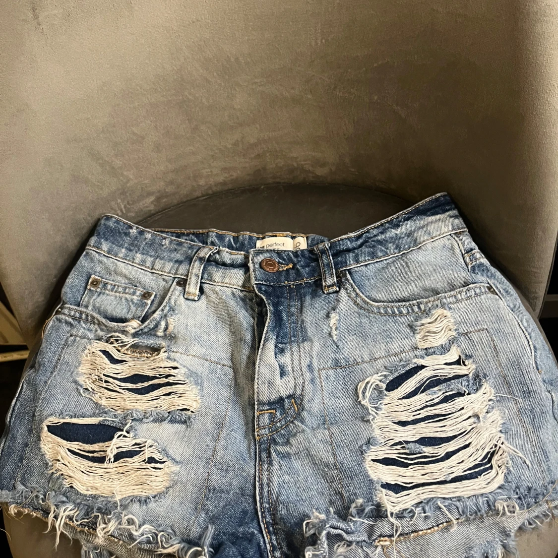 Blå slitna jeansshorts med knappar