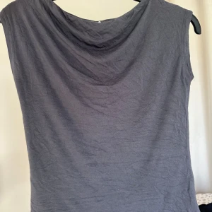 Mörkgrå ärmlös linnetopp - Snygg mörkgrå ärmlös linnetopp med draperad halsringning. Enkel och stilren modell som passar perfekt. Hör av er vid frågor!💖