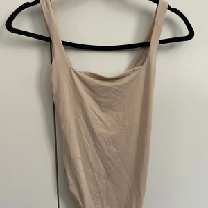 Beige body från BERSHKA  - Snygg body från BERSHKA. Perfekt att matcha med jeans eller kjol för en clean look. Tunt och mjukt material som känns skönt mot huden.