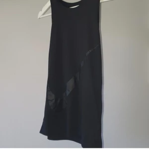 Svart Nike Dri-Fit linnetopp S - Svart topp från Nike med stor ton-i-ton Swoosh-logga framtill. Modellen är ärmlös och tillverkad i Dri-Fit-material som andas, perfekt för träning. Sportig och stilren look som passar dig som gillar att sticka ut på gymmet.