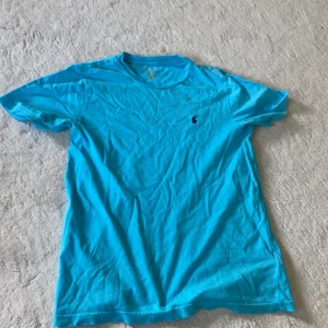 Turkos t-shirt från Polo Ralph Lauren - Snygg turkos t-shirt från Polo Ralph Lauren med klassisk passform och liten broderad logga på bröstet. Tillverkad i mjuk bomull och har rund halsringning samt korta ärmar. Perfekt för en chill och stilren look. Pris kan diskuteras vid snabb affär passar ca 150-165