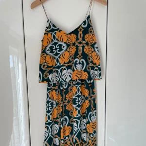 Mönstrad sommarklänning från H&M - Klänning från H&M som ser ut som ett set med linne och kjol (se baksidan av klänningen på bild 3). Snygg detalj. 