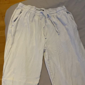 Vita linnebyxor med snörning - Luftiga vita linnebyxor med elastisk midja och snörning. Byxorna har sidfickor fram och en bakficka, perfekt för en avslappnad och chill stil. Materialet är lätt och passar grymt bra till varma dagar.