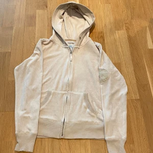 Sammets hoodie - Beige sammets hoodie från Greenwich Village med små defekter(se bild 5). Det står storlek L men skulle säga att den sitter som en M, dock så är tyget rätt stretchigt så skulle nog funka för någon som vanligtvis har L också.