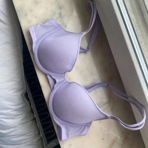 Ljuslila bh från Calvin Klein - Supersnygg ljuslila bh från Calvin Klein med vadderade kupor och justerbara axelband. Mjuk och stretchig känsla i syntetmaterial, väldigt bekväm. Banden går att ta av baktill så man kan använda den som en bandeu bh också. Använt en gång.  