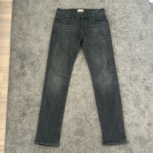 Grå slim straight jeans Jack & Jones - Slim straight fit jeans från Jack & Jones i en snygg grå tvätt. Klassisk femficksmodell med normalhög midja och raka ben. Jeansen är tillverkade i mjukt denimtyg och har diskreta slitningar för en cool look.
