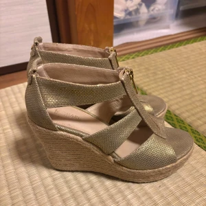 Guldiga wedge-sandaler Michael Kors - Vintage michael kors klackar, limmet har blivit lite gult med tiden (se bild) men annars väldigt fint skick. Skimrigt guld. Står storlek 36, men passar bäst på 37!