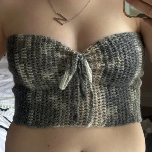Virkad tubtop  - Säljer en handvirkad tubtopp i gråa och beige toner. Toppen är bandeau-modell, croppad och har snygg knytning framtill samt snörning i ryggen för perfekt passform. Skriv för frågor!💞