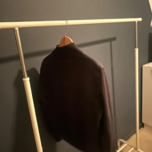 Svart cardigan från Moncler - Svart cardigan från Moncler med quiltad front och dragkedja. Jackan har hög krage och Moncler-logga på ärmen. Materialmix med vadderad framsida och släta ärmar ger en clean och modern look. Perfekt för dig som gillar stilren design. Storlek 1=s