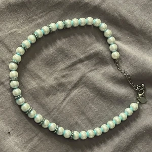 Pärlhalsband Med Silverdetaljer - Snyggt halsband med glansiga pärlor i vitt och ljusblått, varvat med små silverfärgade detaljer mellan pärlorna. 🍒
